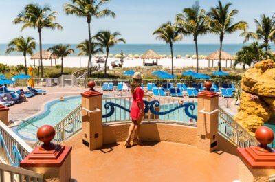 Woman stands on the steps overlooking the pool and Fort Myers Beach