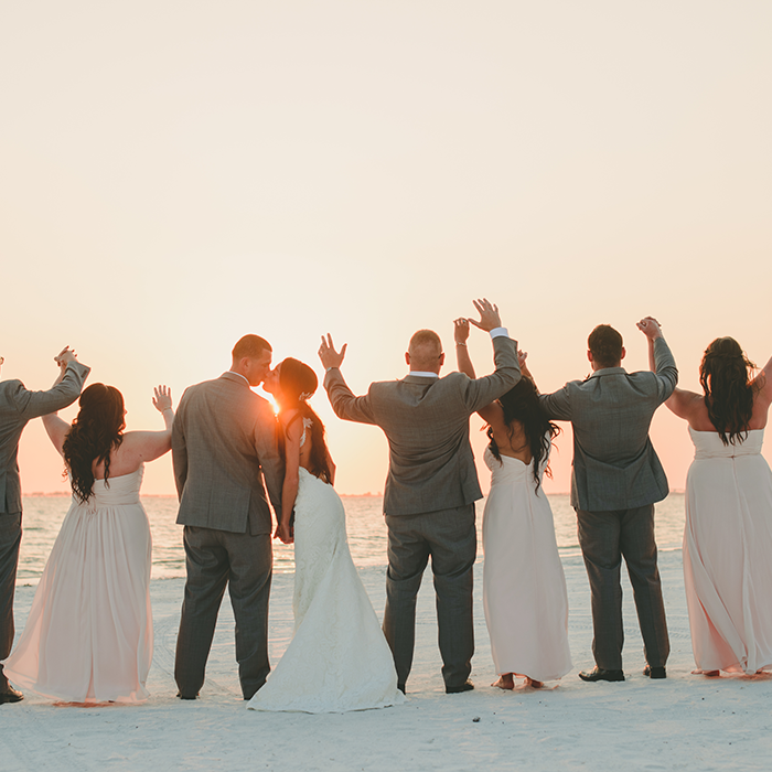 Newlyweds embrace by the ocean during sunset