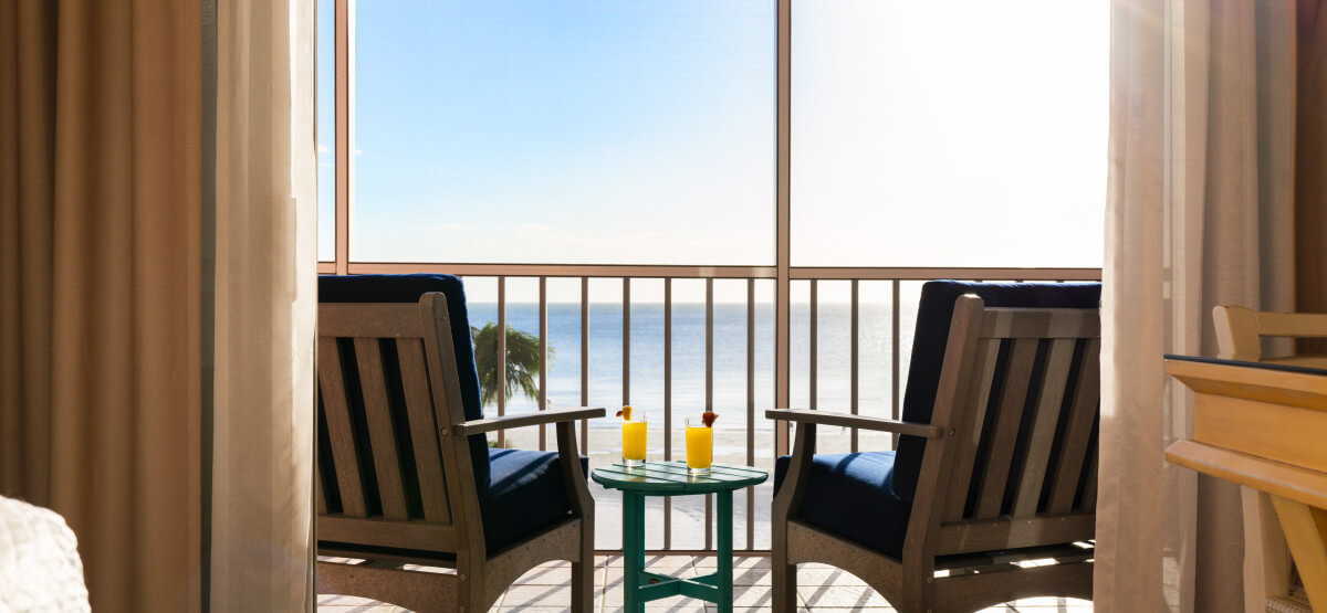 Sun settting in front of private balcony with two chairs and drinks