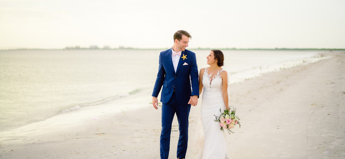 A bride and groom take wedding photos on the beach