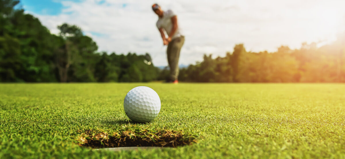 Golf ball near hole just hit by golfer