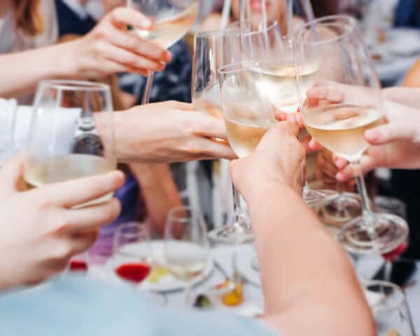 A group of people clinking glasses filled with white wine in a celebratory toast.