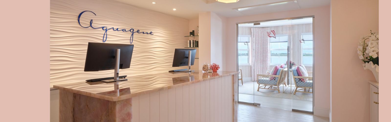 Reception desk with the Aquagene logo on a textured wall, opening into a waiting area with seating.